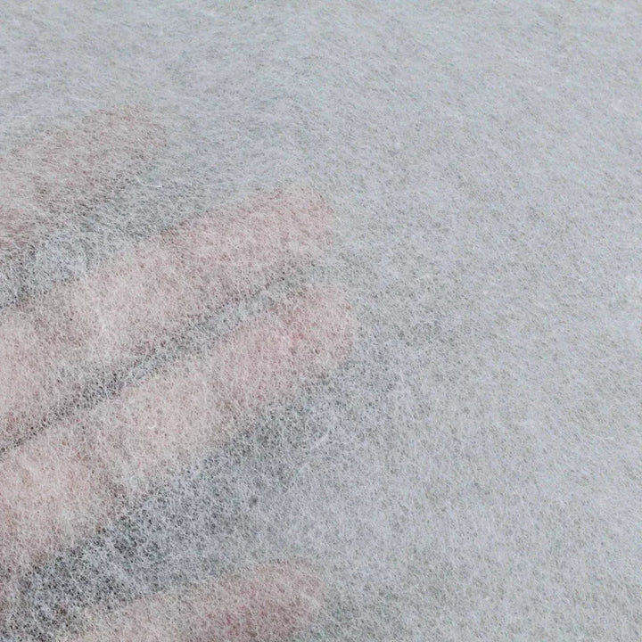 A hand presses under a thin, semi-transparent sheet of Kozo Studios Conservator No.1 washi paper (8.5 gsm; 15 sheets/pack), making the fingers faintly visible through its textured surface.