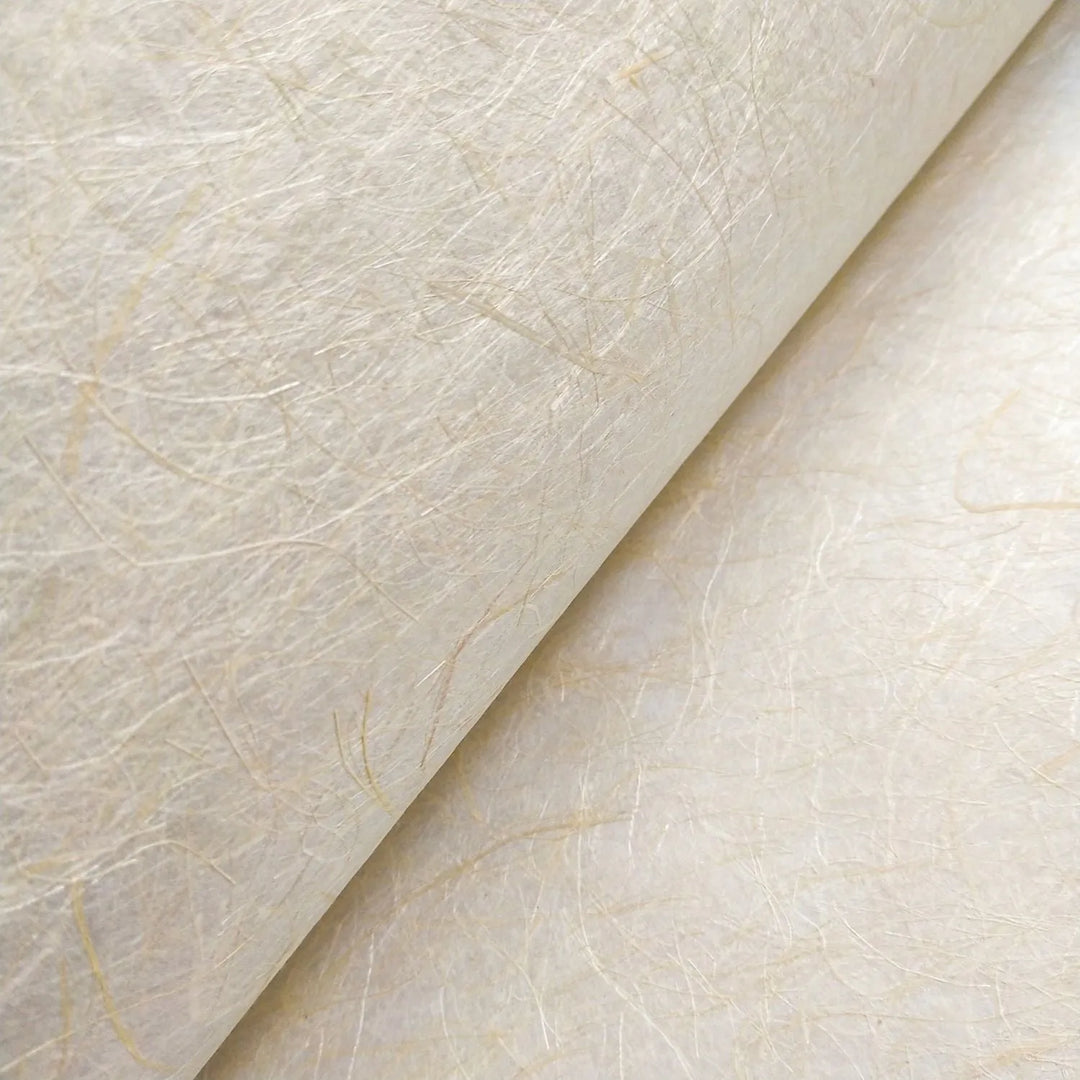 A close-up of Kozo Studios Kinwashi (Natural Abaca Paper) reveals a textured beige surface with visible fibers, slight roughness, light color variations, and subtle thread-like patterns due to its unique Kozo pulp blend.