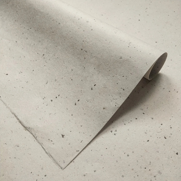 Kozo Studio Chiri Kozo Paper Natural shown folded, highlighting the fine handmade paper quality and grey-specked mulberry paper appearance.
