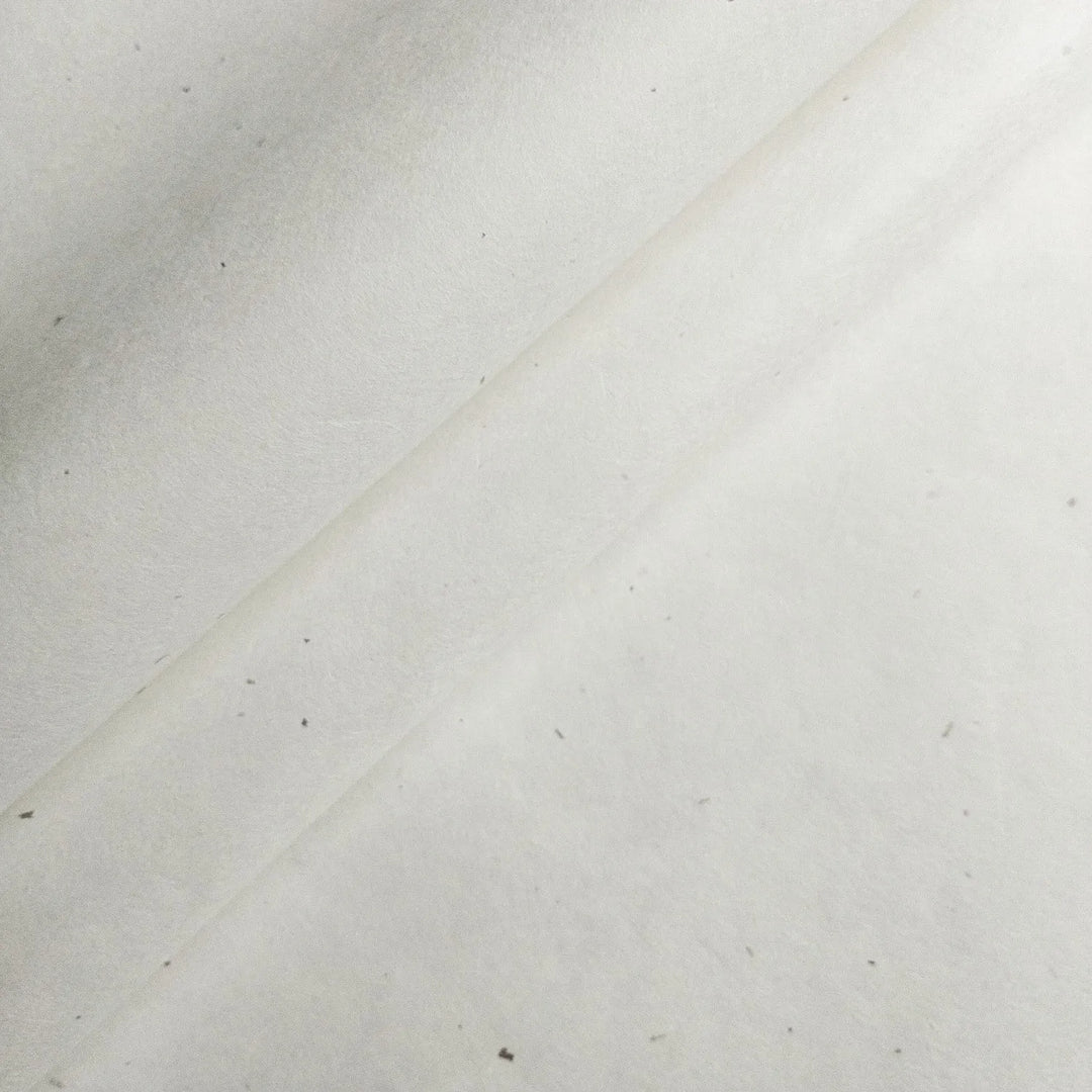 A close-up of Kozo Studios Chiri Kozo Paper White (45 gsm) reveals a textured mulberry surface with faint diagonal lines and tiny specks, highlighting its handmade or recycled quality.