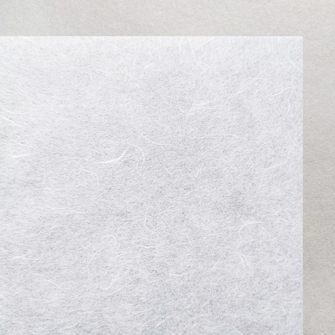 A close-up of Kozo Studios A4 Decoupage Unryu Mulberry Paper (30 gsm, 40 sheets), featuring visible fibers and excellent ink absorption, displayed on a smooth light gray background.