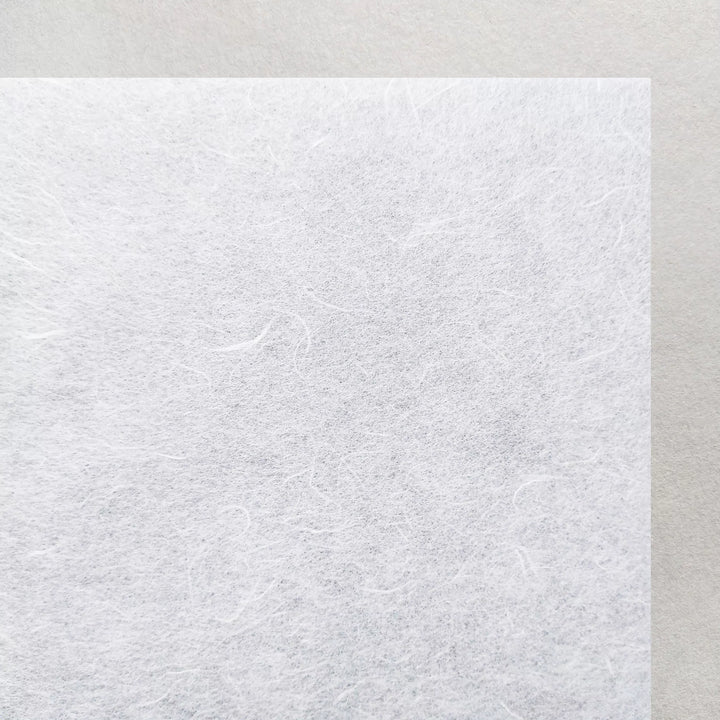 A close-up of Kozo Studios A4 Decoupage Unryu Mulberry Paper (30 gsm, 40 sheets), featuring visible fibers and excellent ink absorption, displayed on a smooth light gray background.