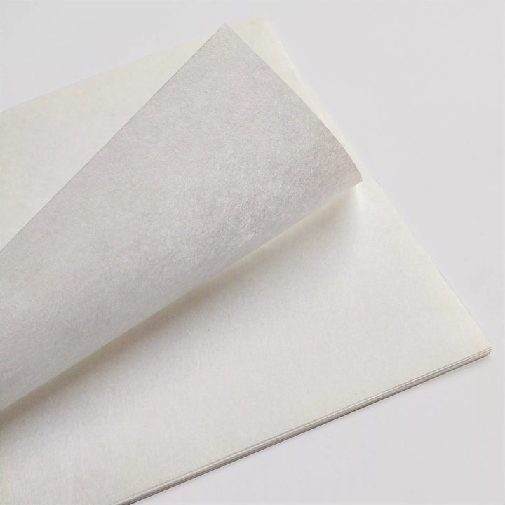 A partially curled top sheet in a stack of A4 Extra Thin White Kozo Paper, 10 sheets at 25 gsm by Kozo Studio, set against a plain light background.