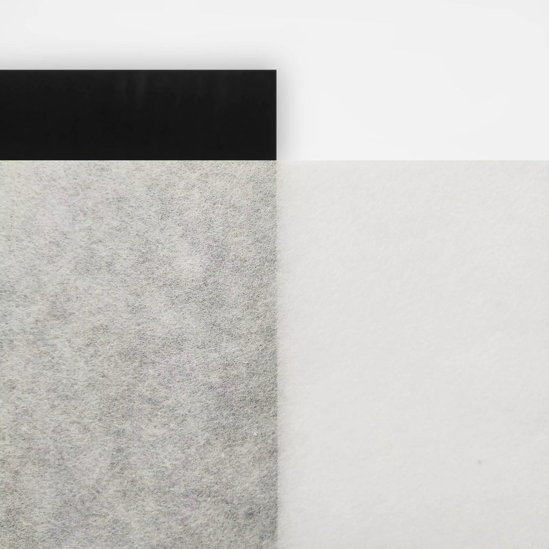 A minimal abstract image features Kozo Studios A4 Decoupage Plain Mulberry Paper (40 Sheets, 30 gsm): a black stripe at the top left, a textured gray mulberry paper rectangle beneath highlighting ink absorption, and a smooth white area on the right.
