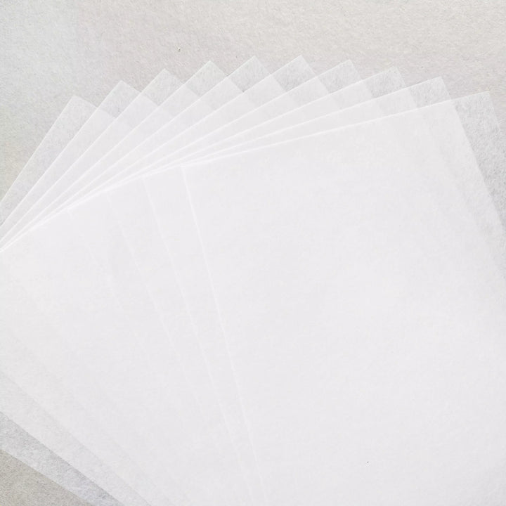 A fan arrangement of Kozo Studio’s A4 Decoupage Plain Mulberry Paper (40 Sheets, 30 gsm), translucent white and known for ink absorption, is displayed on a similarly textured white surface.