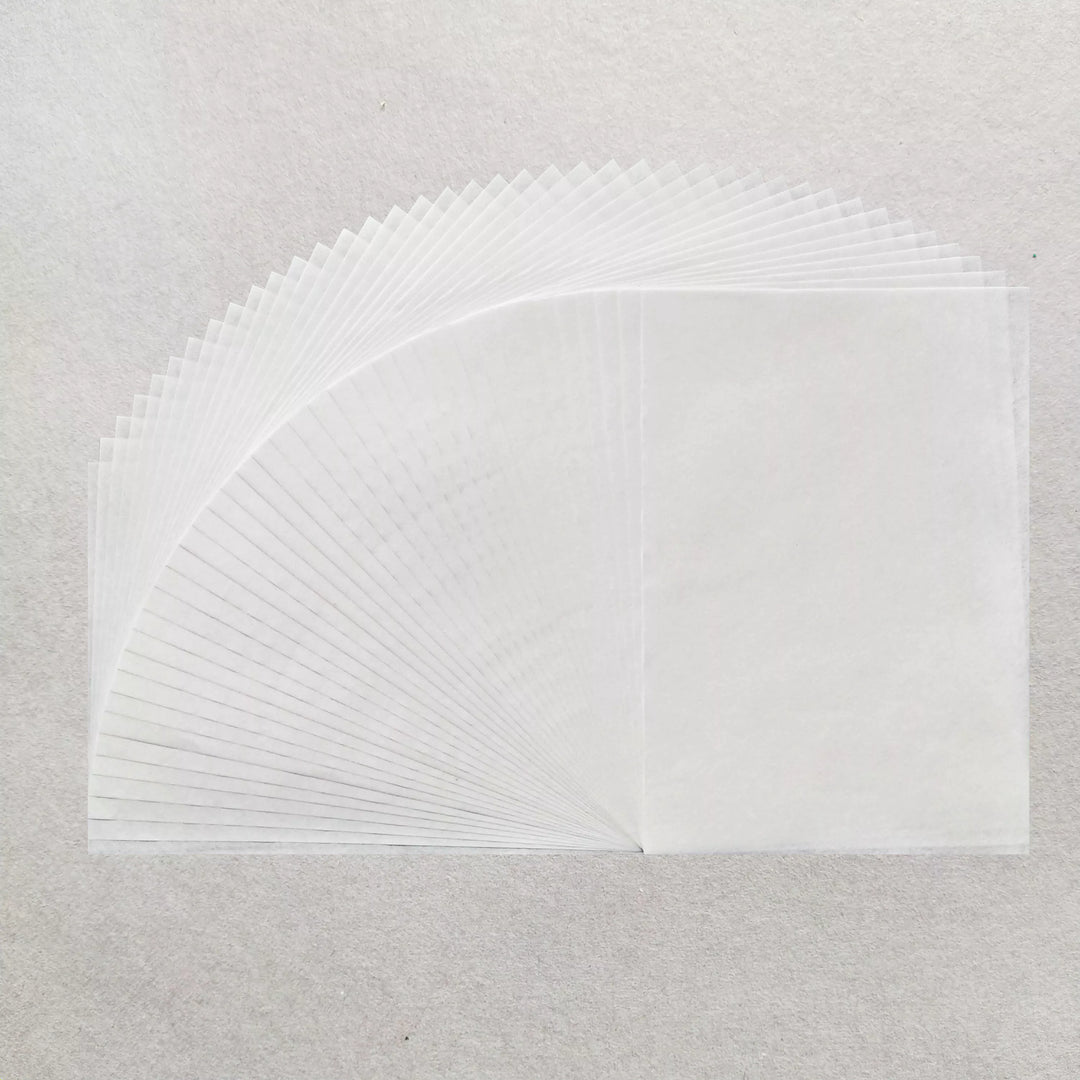 A stack of Kozo Studio A4 Decoupage Plain Mulberry Paper (40 Sheets, 30 gsm) is fanned out on a light grey surface, highlighting the delicate texture, overlapping edges, and superb ink absorption of each translucent sheet.