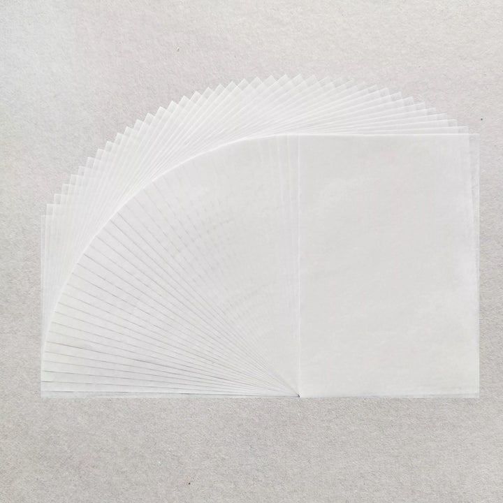 A stack of Kozo Studio A4 Decoupage Plain Mulberry Paper (40 Sheets, 30 gsm) is fanned out on a light grey surface, highlighting the delicate texture, overlapping edges, and superb ink absorption of each translucent sheet.