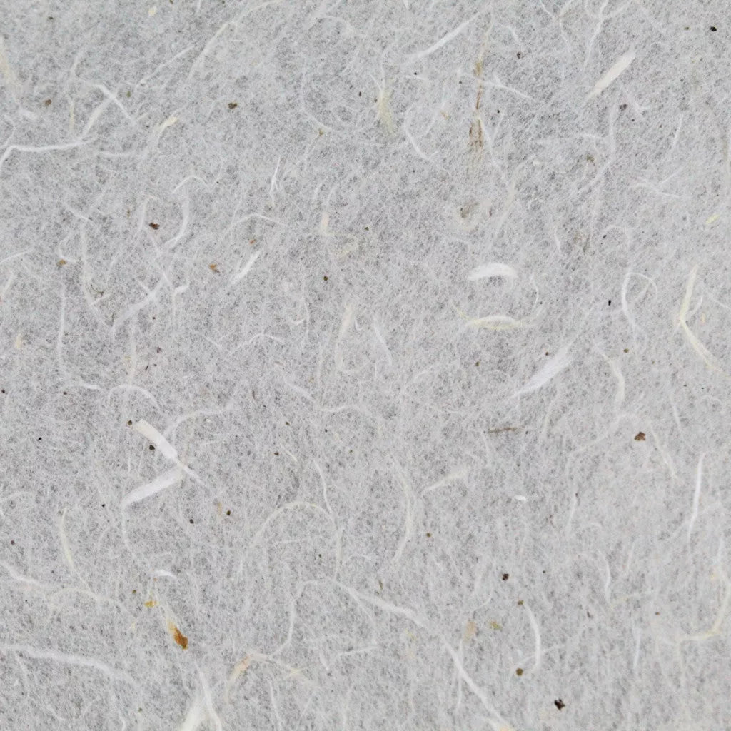 A close-up of Kozo Studios Water-resistant Kozo Paper (Natural) reveals a textured, off-white surface with visible fibers and specks, reminiscent of mulberry paper. The uneven pattern is created by intertwined strands across the paper.