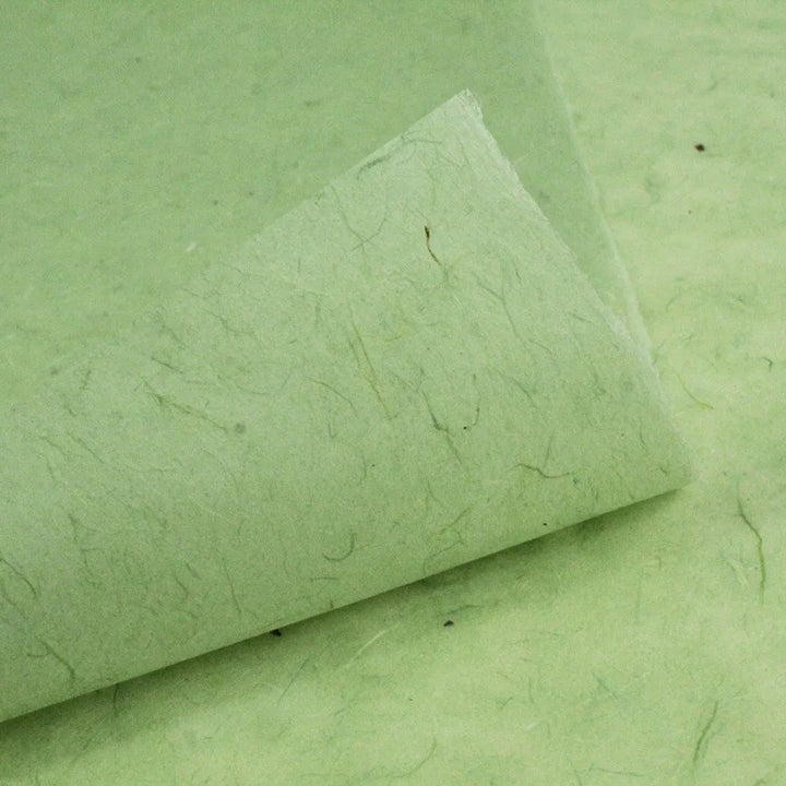 Close-up of Water-resistant Kozo Paper (Mint) by Kozo Studio, showcasing its textured surface with visible fibers. The gently curled corner reveals the underside, highlighting its natural, handmade appearance reminiscent of traditional mulberry paper.