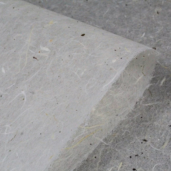 Close-up of a Water-resistant Kozo Paper (Natural) sheet by Kozo Studio, highlighting its textured surface with visible mulberry fibers and small flecks. The light gray papers slightly curled edge emphasizes its natural, organic appearance.