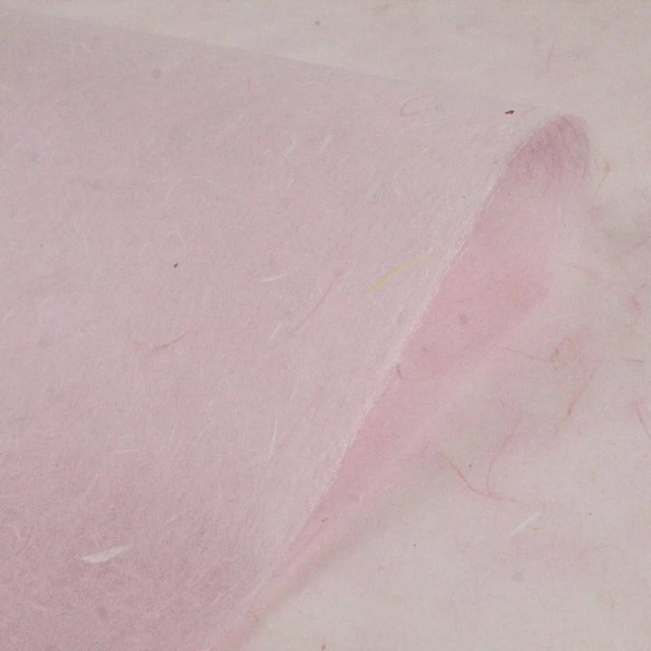 Close-up of Kozo Studios Water-resistant Kozo Paper in pink, featuring a textured, fibrous surface of a delicate mulberry paper with a gently curved edge.