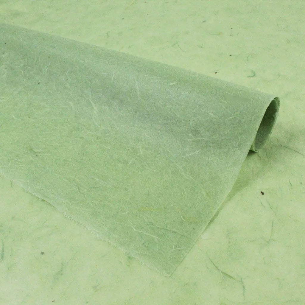 A roll of Kozo Studios Water-resistant Kozo Paper (Mint) unfolds on a matching surface, displaying visible fibers with a soft, natural look.