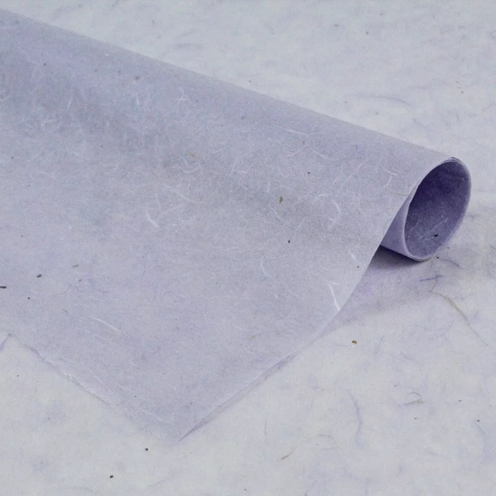 A sheet of thin, translucent Water-resistant Kozo Paper (Lavender) by Kozo Studio is rolled at one edge and rests on a similar background, showcasing a subtle texture with visible fibers.