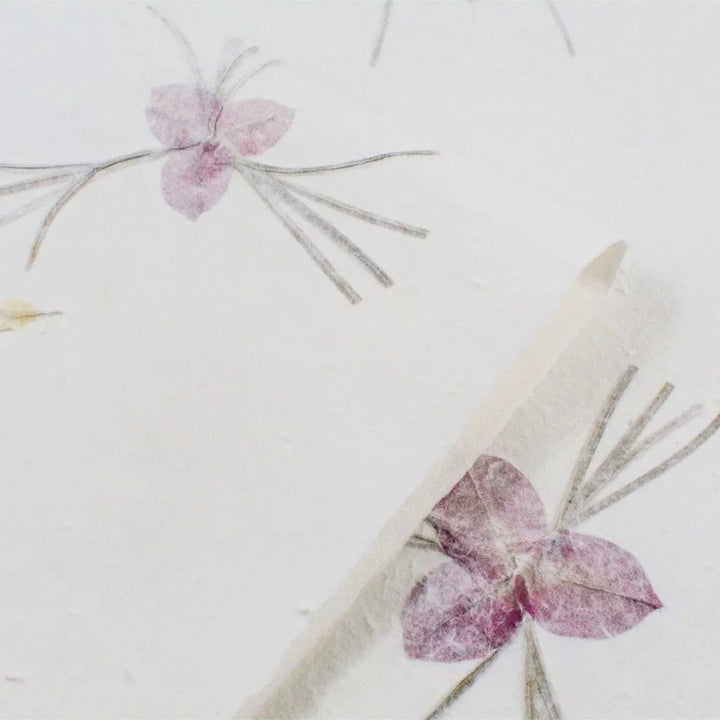 Close-up of handmade mulberry paper by Kozo Studio, showcasing delicate floral patterns and natural curled edges.