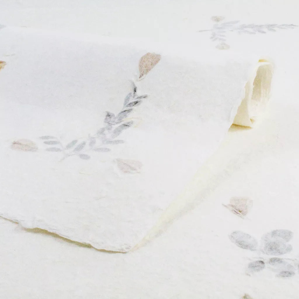 Close-up of Kozo Studio handmade paper featuring dried flowers pressed into white mulberry paper, showcasing a vintage rustic charm perfect for creative projects.