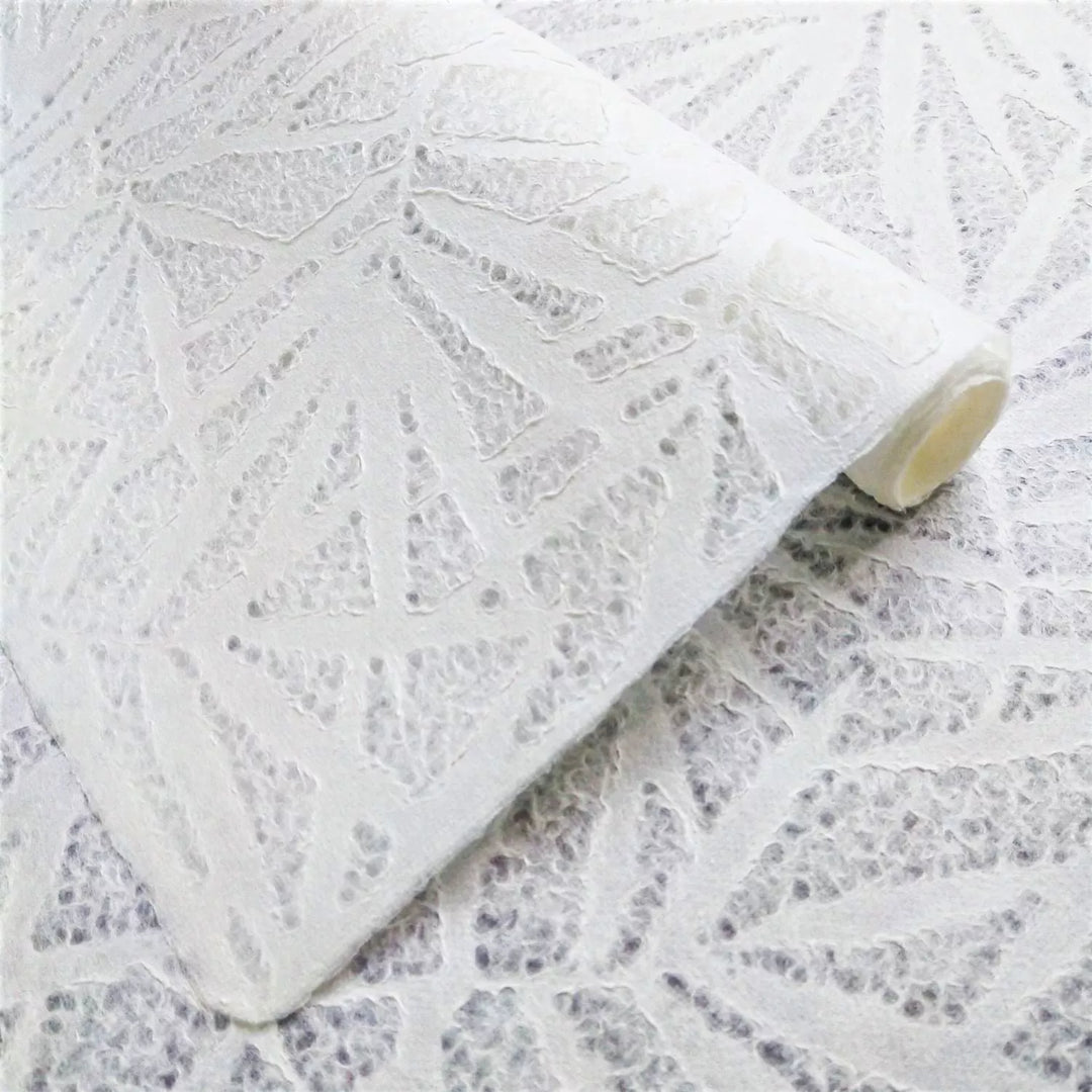 A close-up of Handmade Lace Kozo Paper (Bamboo) by Kozo Studio shows a white textured of mulberry paper, featuring an intricate bamboo pattern. The material is folded and layered to highlight its texture.