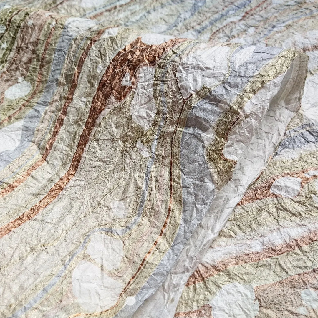 A close-up of Milano Kozo Paper - Design 10 (White) by Kozo Studio reveals swirling, marbled patterns and Mulberry textures in earthy tones reminiscent of a topographic map, with layered flowing lines adding depth and a tactile quality.
