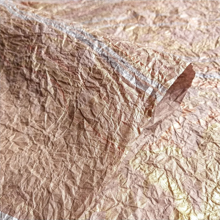 The Milano Kozo Paper - Design 11 (Taupe) by Kozo Studio showcases a crumpled, textured surface in bronze, gold, and silver tones. It is a mulberry paper with irregular patterns with a rich, tactile appearance.
