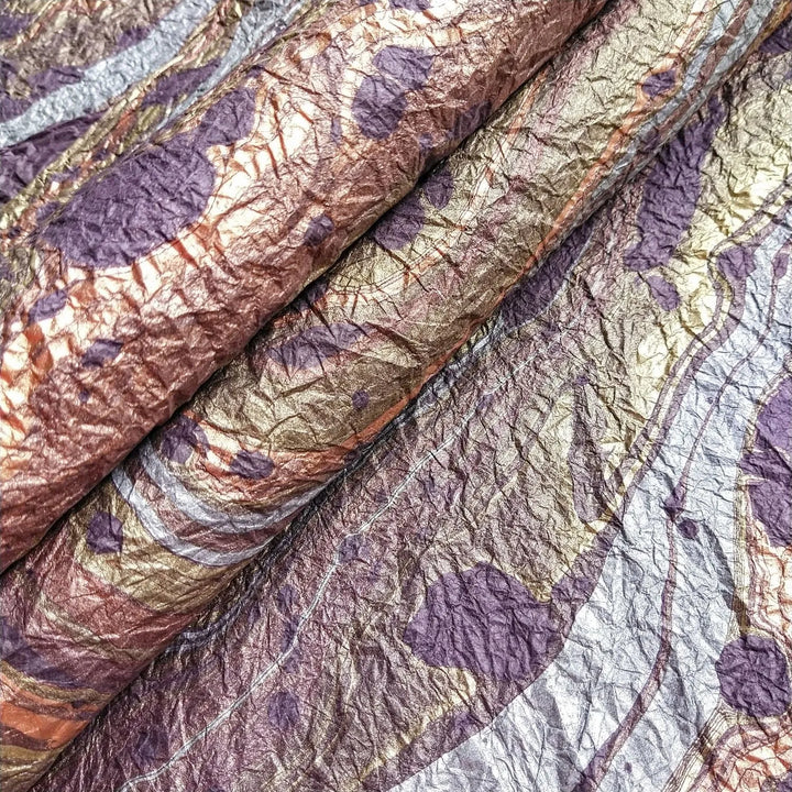 Handmade marbled mulberry paper in purple from Kozo Studio, showcasing intricate oil-based swirling patterns and a soft fabric-like texture.