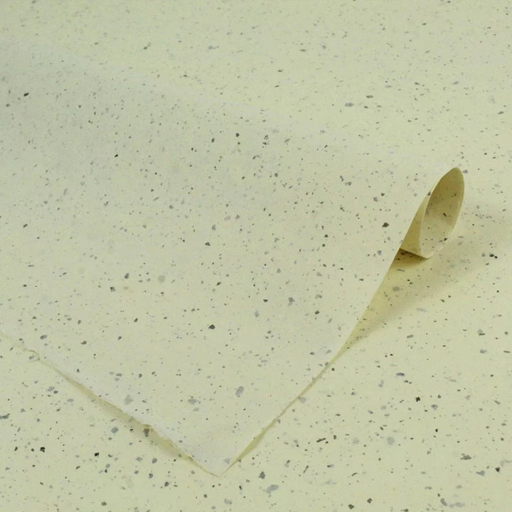 Artistic close-up of mulberry paper by Kozo Studio, featuring natural speckles and elegant layering of semi-translucent handmade paper for crafts and design.
