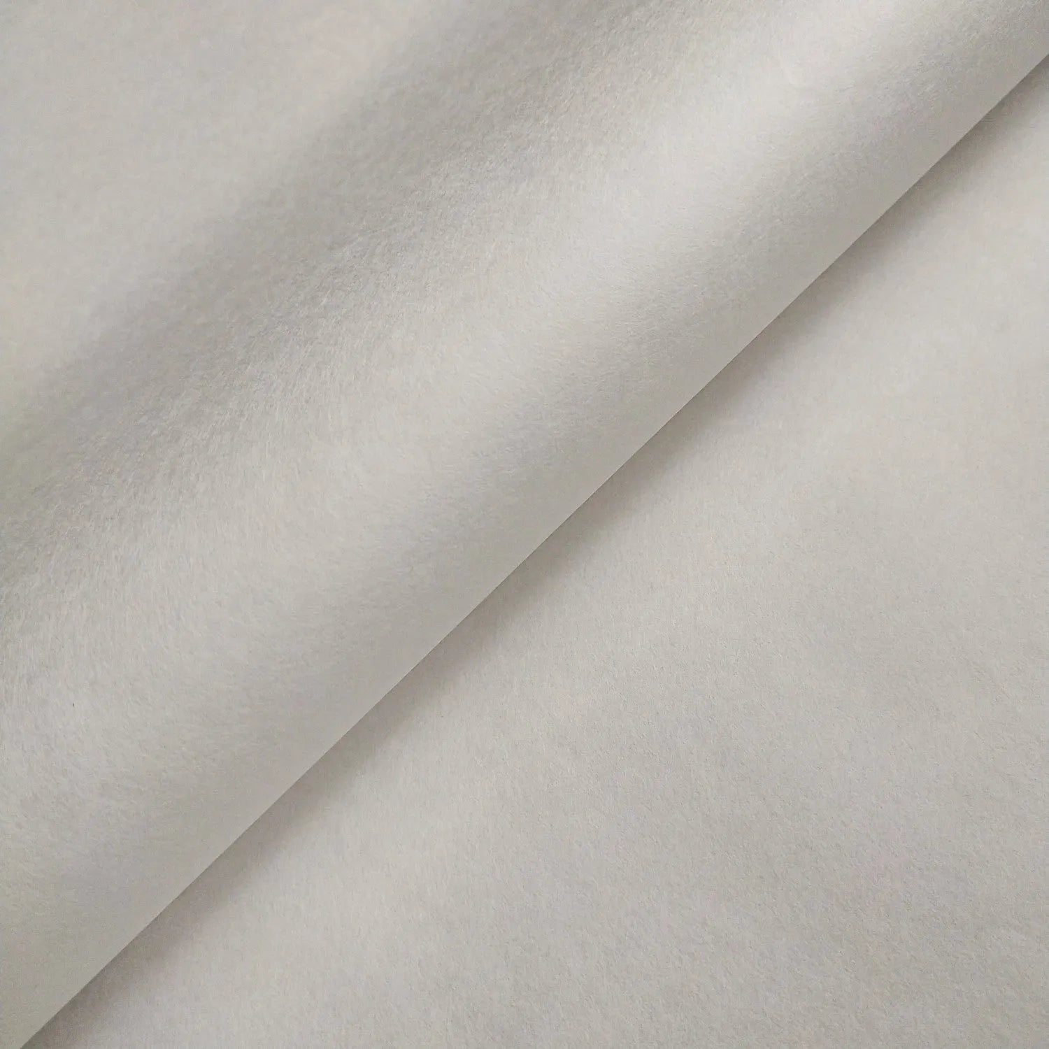 Close-up of two overlapping sheets of Kozo Studio Thin White Kozo Paper Roll (45 gsm), featuring a smooth, soft texture and light gray tone, forming a diagonal line where they meet.