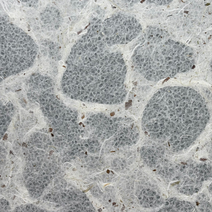 Close-up of Tidal Lace Kozo Paper (Chiri) by Kozo Studio, featuring textured handmade surfaces with white fibers, gray patches, and brown flecks for an organic, layered look popular among paper artists.