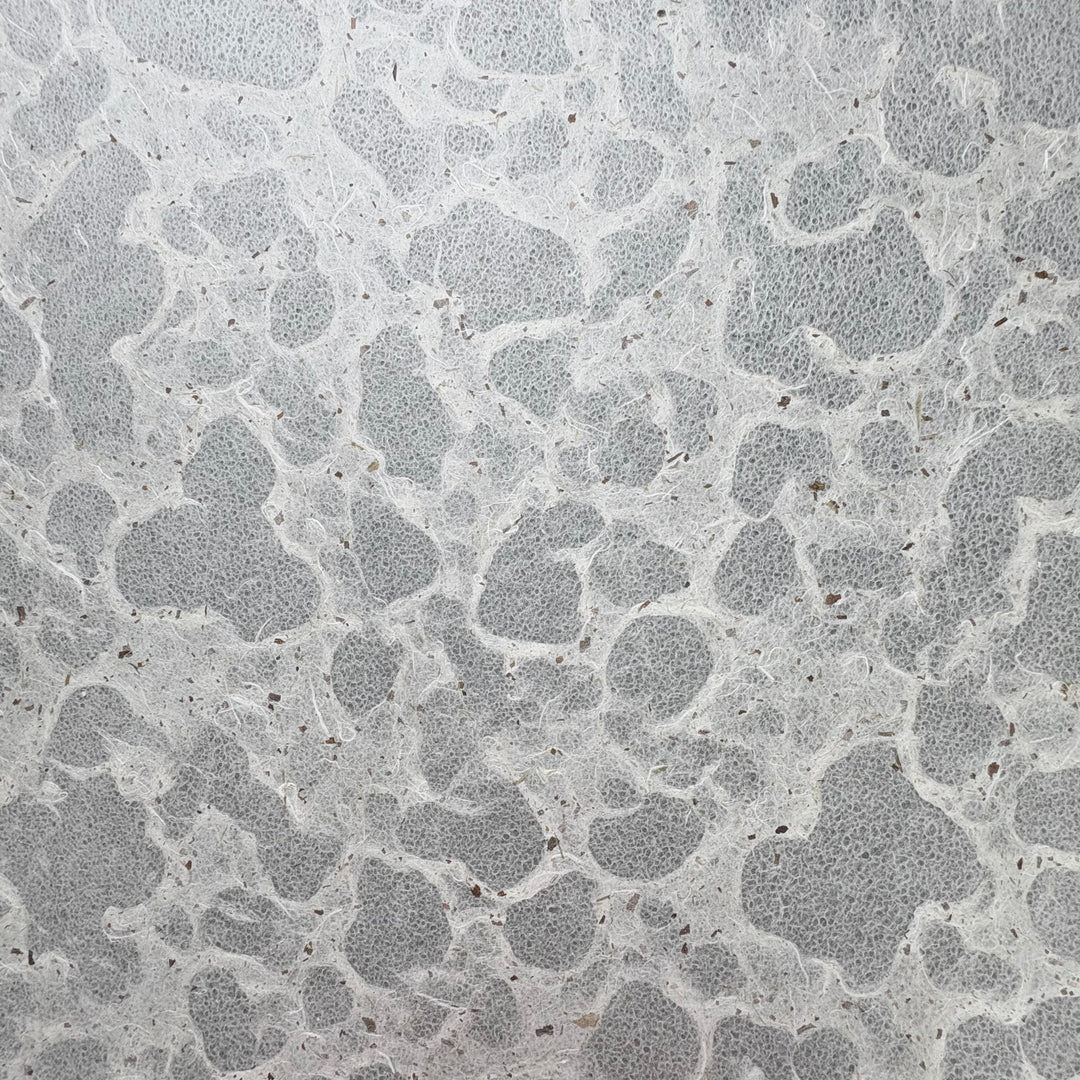 Tidal Lace Kozo Paper (Chiri) by Kozo Studio features a textured, handmade look with an irregular stone-like pattern in light gray, accented by darker gray lines and scattered small brown flecks.