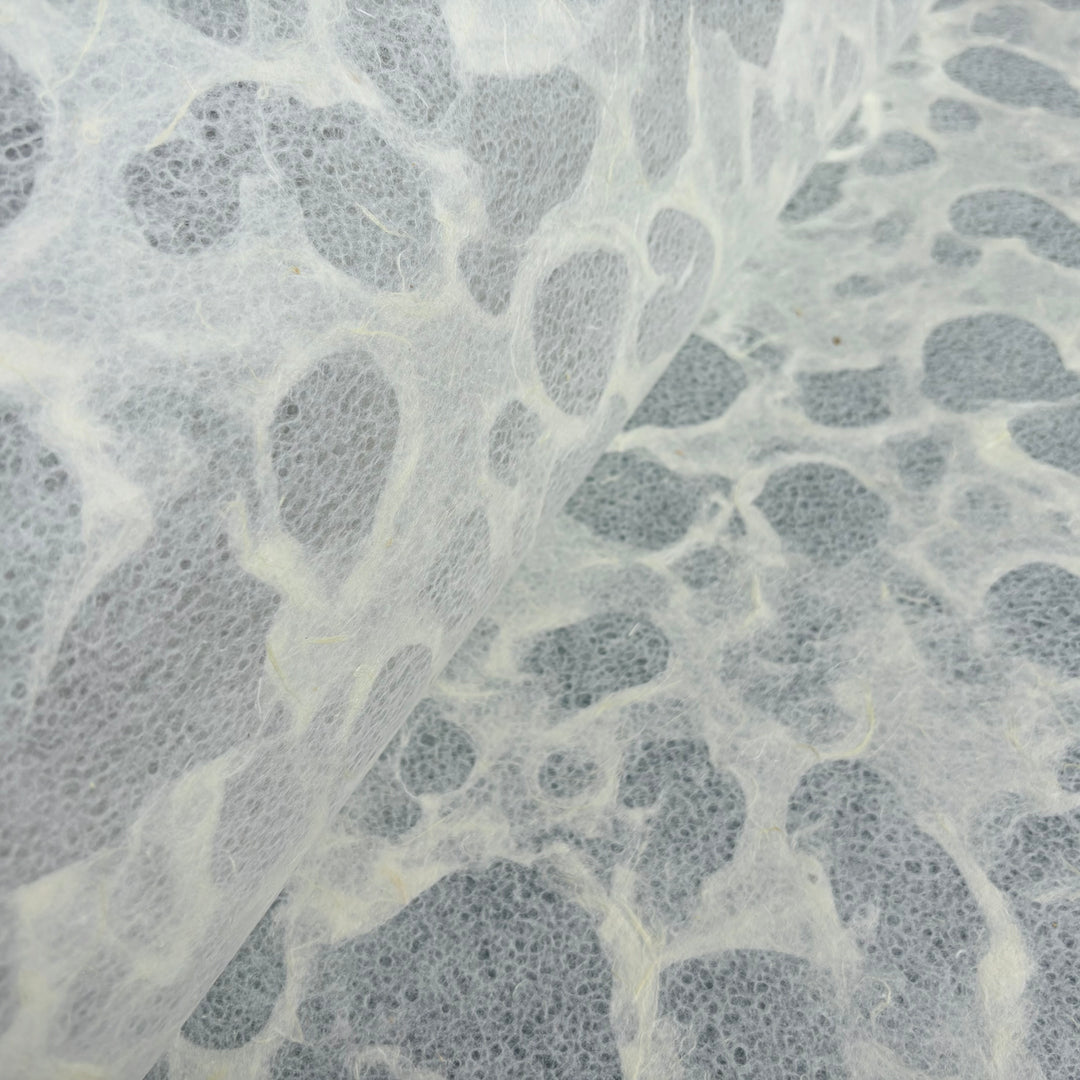 A close-up of Tidal Lace Kozo Paper (Unryu) by Kozo Studio reveals translucent, textured handmade paper with irregular, cloudy patterns and soft, overlapping shapes for an abstract, organic look.