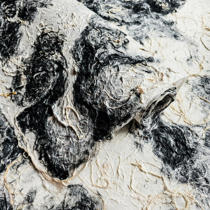 A sheet of Kozo Studio mulberry paper featuring a textured, medium-weight surface with a natural black and white color mix.