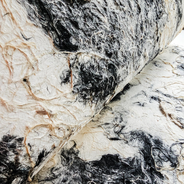 Kozo Studio's handmade paper crafted from mulberry showing a rough finish and harmonious blend of earthy black and white shades.