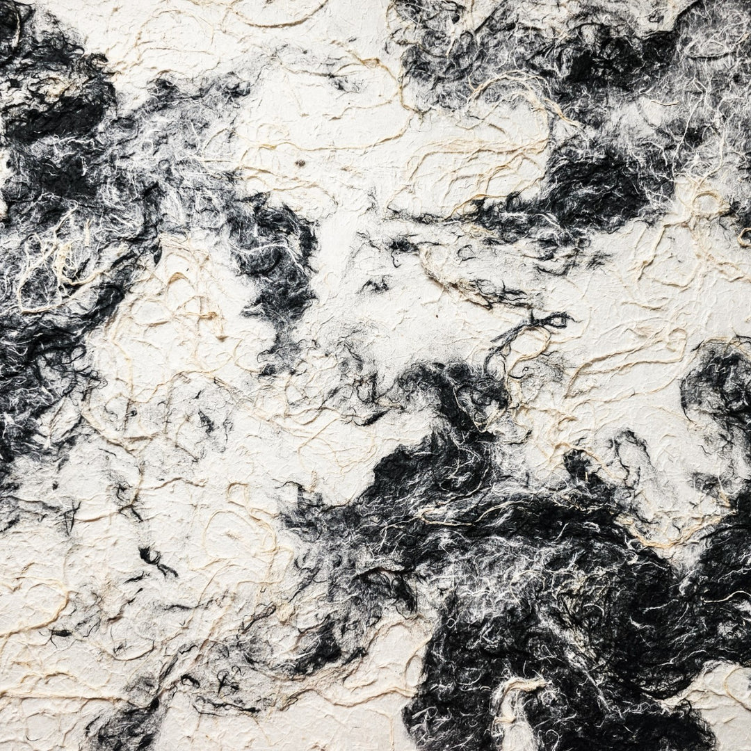 The Handmade Earthy Harmony Kozo Paper by Kozo Studio features a dynamic and fluid black-and-white marbled pattern, resembling swirling smoke or natural stone, with textures akin to delicate mulberry paper fibers, creating a visually striking contrast.