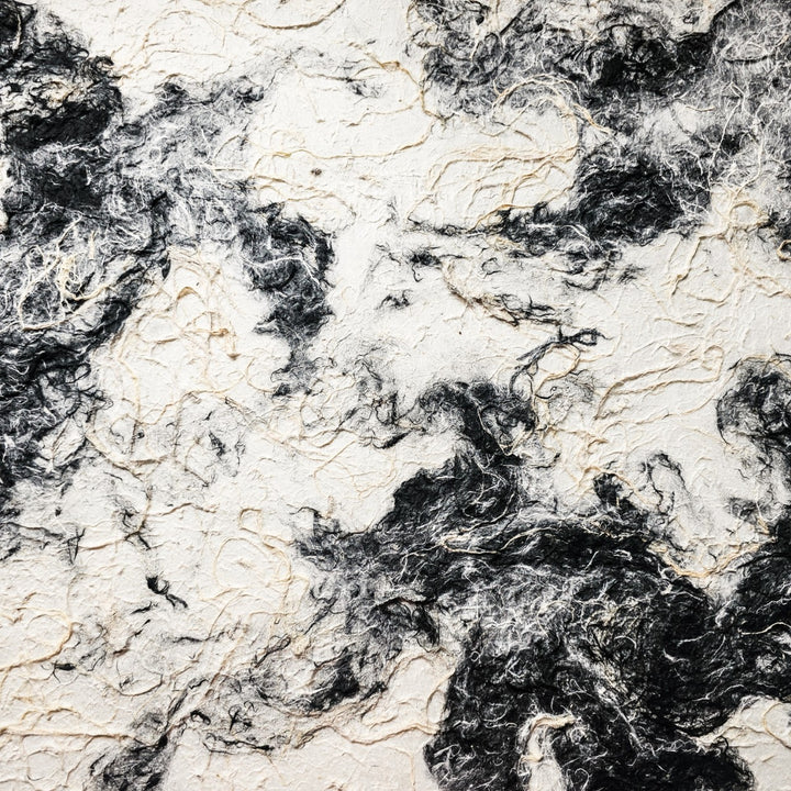 The Handmade Earthy Harmony Kozo Paper by Kozo Studio features a dynamic and fluid black-and-white marbled pattern, resembling swirling smoke or natural stone, with textures akin to delicate mulberry paper fibers, creating a visually striking contrast.