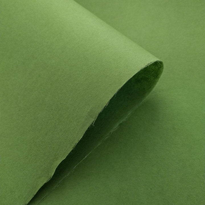 Textured view of fern green Kozo Studio handmade paper, crafted from mulberry fibers, with shadows enhancing its solid color and refined surface.