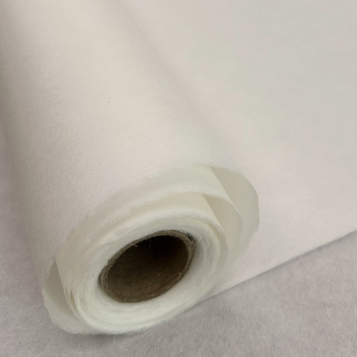 Eine Nahaufnahme der dünnen weißen Kozo-Papierrolle (45 g/m²) von Kozo Studio, teilweise abgerollt, zeigt ihre glatte Textur und das innere Papprohr – ideal für feine Pinselarbeiten.